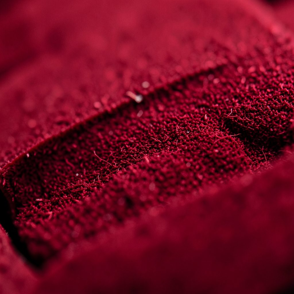 Close-up texture of a felt playing surface in deep maroon and olive tones with a quiet, focused mood
